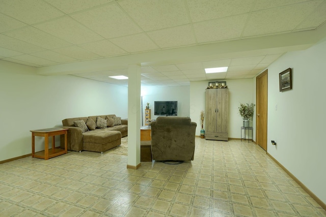 living area featuring baseboards and a drop ceiling