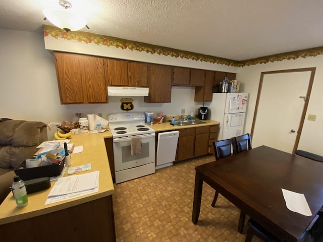 kitchen with tile patterned floors, white appliances, light countertops, under cabinet range hood, and a sink