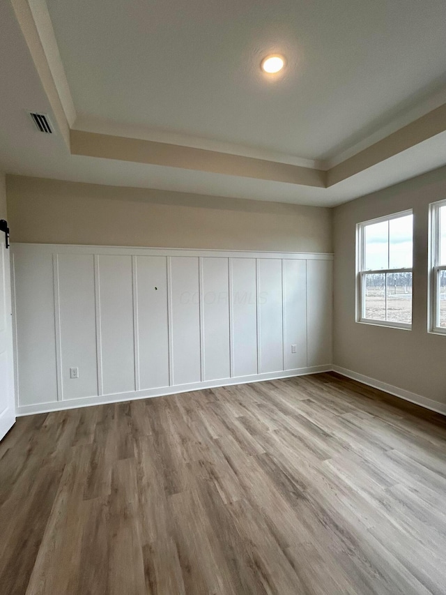 empty room with visible vents, wood finished floors, and a decorative wall