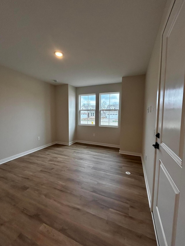 spare room featuring baseboards and dark wood-style flooring