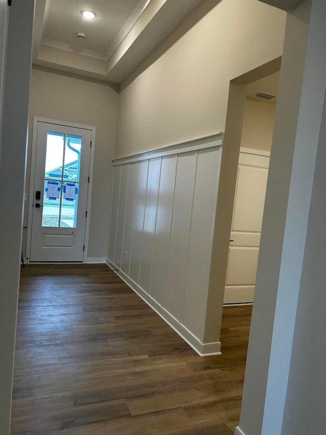 interior space featuring dark wood finished floors, a decorative wall, wainscoting, and a raised ceiling