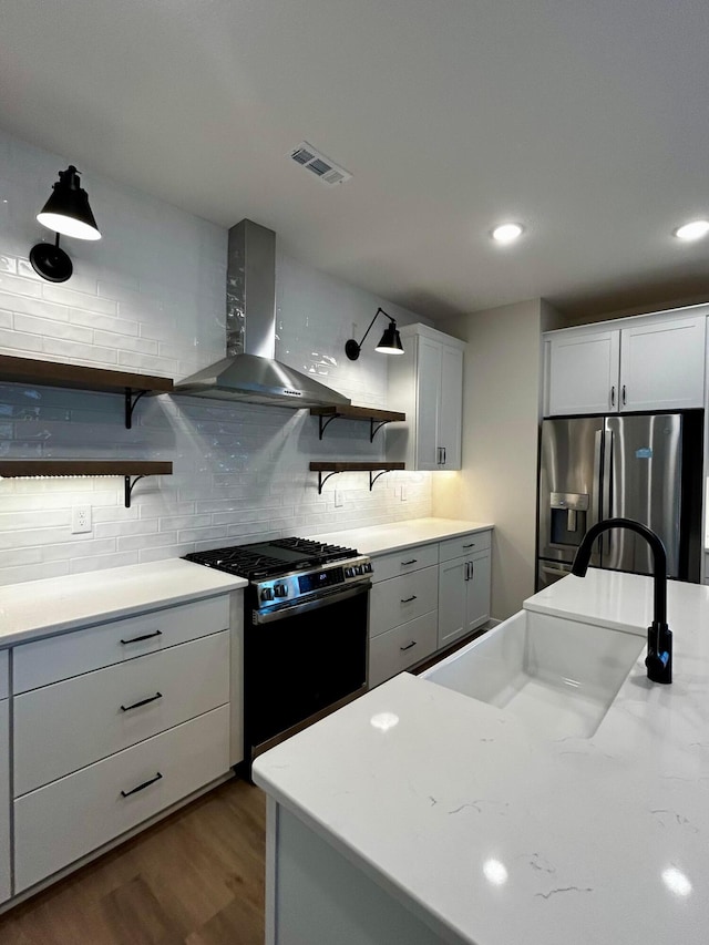 kitchen with stainless steel fridge, open shelves, a sink, black gas stove, and wall chimney exhaust hood