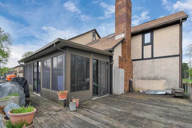 2520 Mccutcheon Rd, Columbus, OH 43219 - rear view of house with a wooden deck, a chimney, a sunroom, and stucco siding