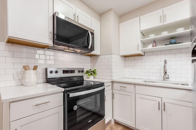 kitchen featuring decorative backsplash, white cabinetry, a sink, and appliances with stainless steel finishes