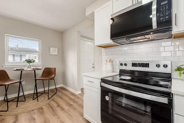 kitchen featuring white cabinetry, light wood-style flooring, stainless steel appliances, and tasteful backsplash
