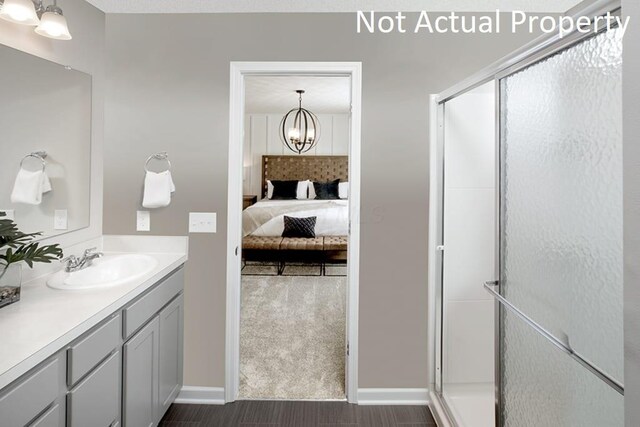 full bath with an inviting chandelier, a shower stall, vanity, ensuite bath, and baseboards