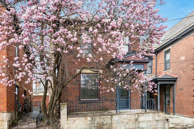 view of property hidden behind natural elements with brick siding
