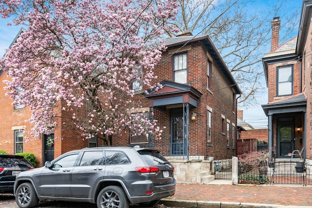 view of front of property with brick siding and fence