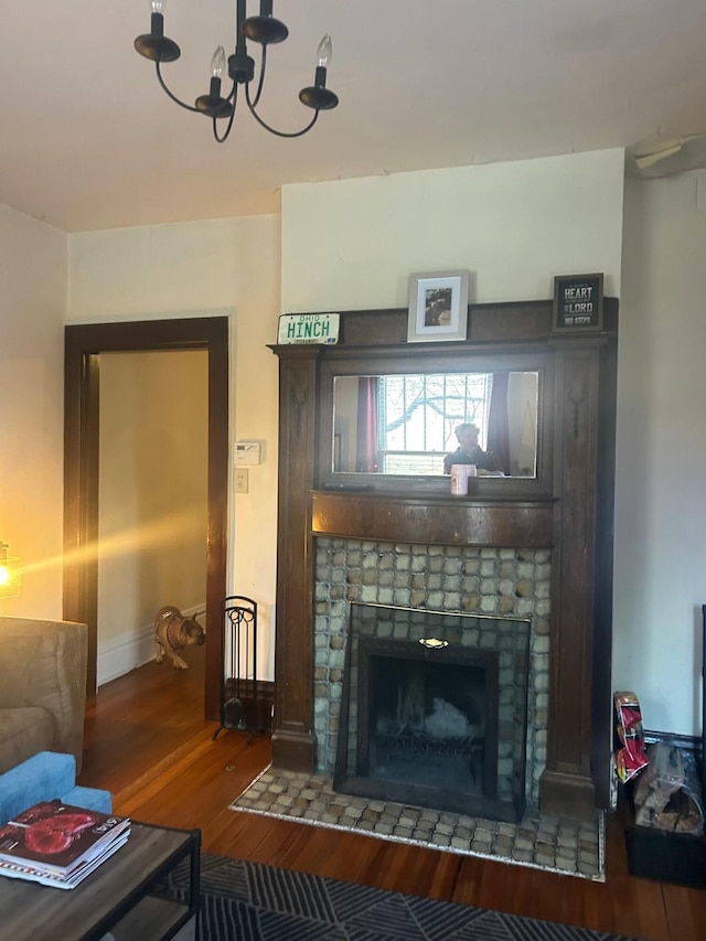 living room featuring a chandelier, a tiled fireplace, and wood finished floors
