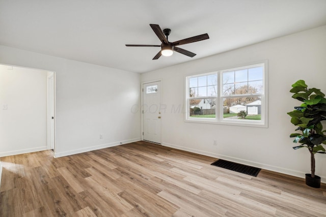 unfurnished room featuring light wood finished floors, baseboards, visible vents, and ceiling fan