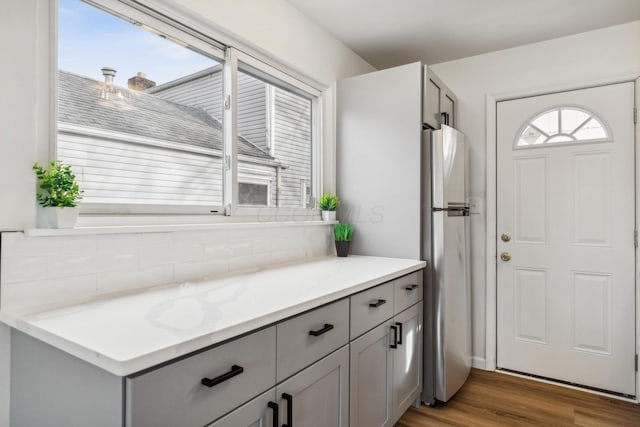 interior space featuring gray cabinetry, wood finished floors, light stone counters, and freestanding refrigerator