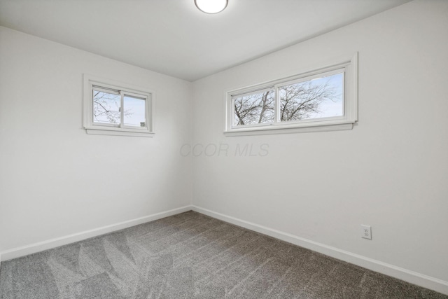 empty room with a wealth of natural light, baseboards, and carpet flooring