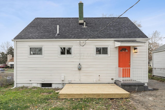 rear view of property with a shingled roof and fence