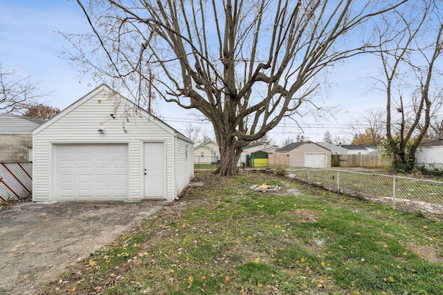 view of yard featuring an outbuilding, driveway, fence, and a detached garage