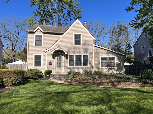 traditional-style house with fence, a chimney, and a front yard