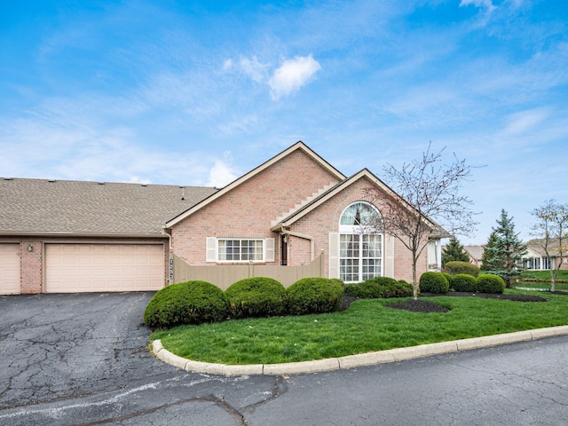 view of front facade featuring brick siding, a front yard, a garage, and driveway