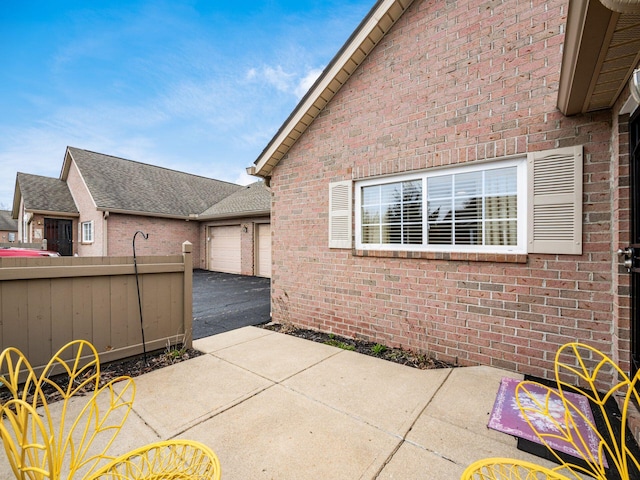 view of patio with fence, a garage, and aphalt driveway