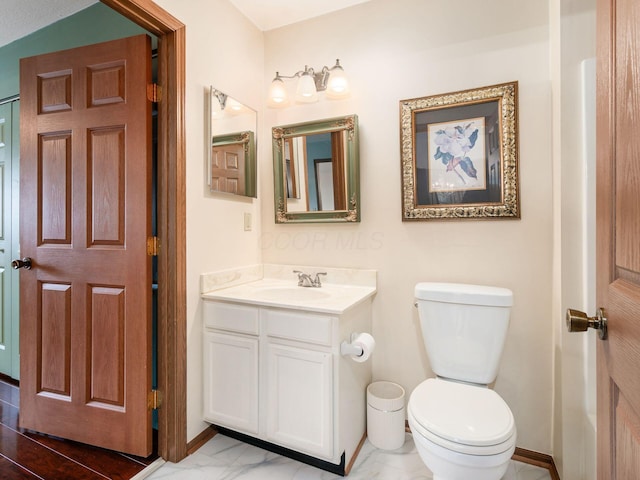 bathroom featuring marble finish floor, vanity, baseboards, and toilet