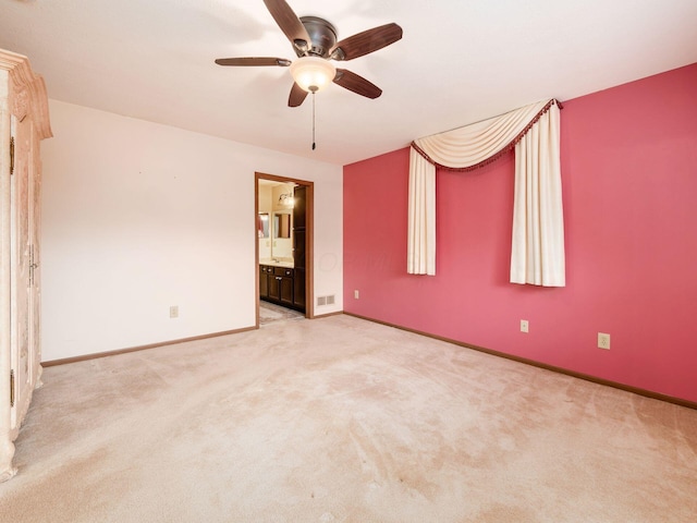 unfurnished bedroom featuring ceiling fan, light colored carpet, ensuite bath, visible vents, and baseboards
