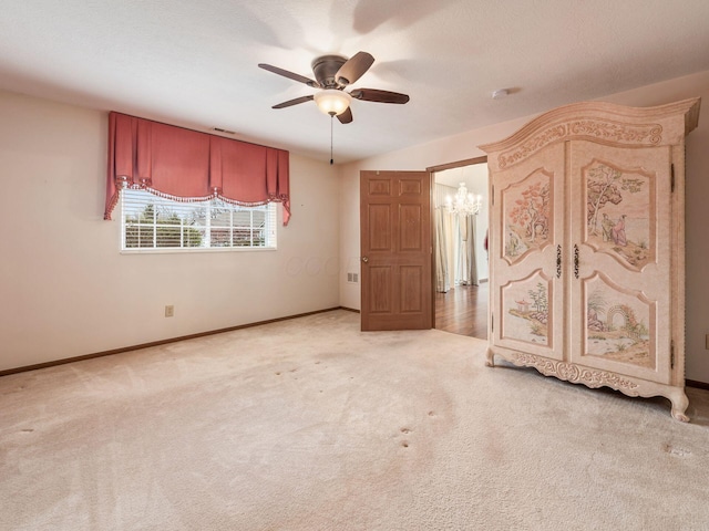 unfurnished bedroom featuring baseboards, light carpet, and ceiling fan with notable chandelier