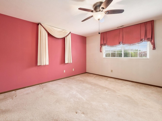 carpeted spare room featuring ceiling fan, baseboards, and visible vents