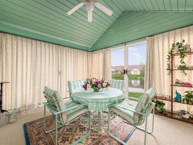 sunroom with a water view, a ceiling fan, carpet, and lofted ceiling