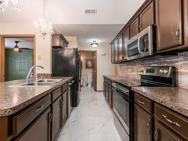 kitchen featuring dark brown cabinets, marble finish floor, dark countertops, a sink, and stainless steel appliances
