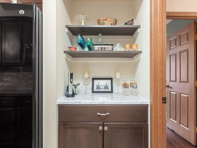 bar with a bar, freestanding refrigerator, and wood finished floors