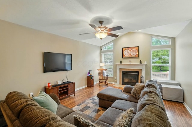 living area with lofted ceiling, wood finished floors, a healthy amount of sunlight, and a ceiling fan