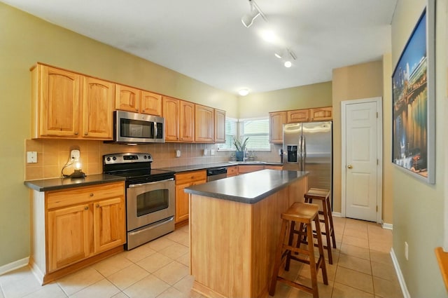 kitchen with tasteful backsplash, light tile patterned floors, stainless steel appliances, a breakfast bar, and dark countertops