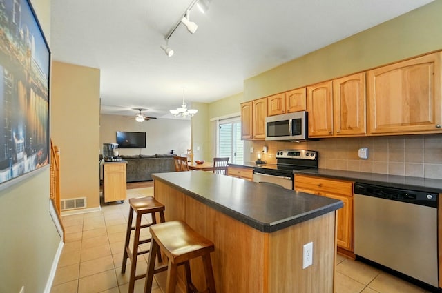 kitchen with tasteful backsplash, dark countertops, stainless steel appliances, light tile patterned floors, and visible vents