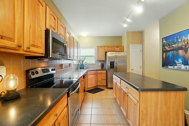 kitchen featuring light tile patterned flooring, tasteful backsplash, appliances with stainless steel finishes, a sink, and a center island