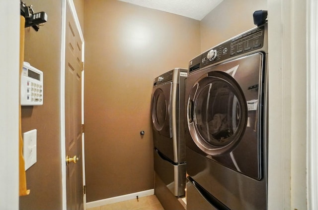 laundry area with light tile patterned flooring, washing machine and dryer, baseboards, and laundry area