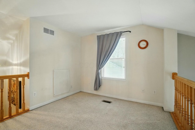 spare room featuring baseboards, visible vents, carpet floors, and vaulted ceiling