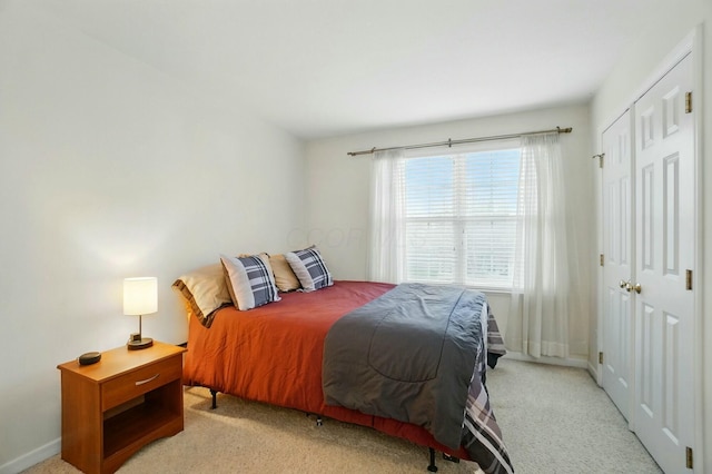 bedroom featuring baseboards, a closet, and light colored carpet