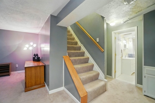 stairway with baseboards, a textured ceiling, and carpet