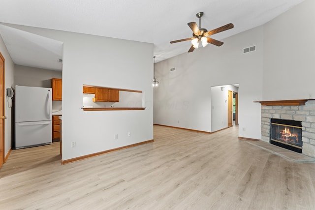 478 Three Oaks Ct, Columbus, OH 43230 - unfurnished living room featuring a ceiling fan, light wood-style floors, a brick fireplace, baseboards, and a towering ceiling