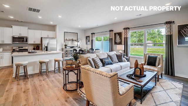 living room featuring light wood-style flooring, baseboards, visible vents, and recessed lighting