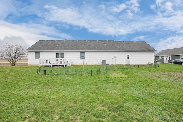 rear view of house featuring a lawn, fence, central AC, and a deck
