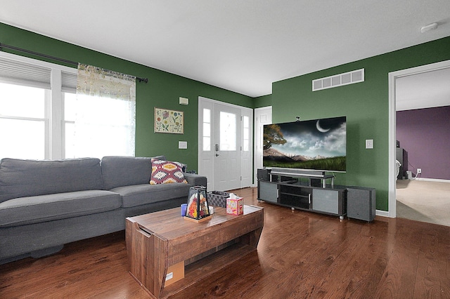 living area with baseboards, visible vents, and wood finished floors