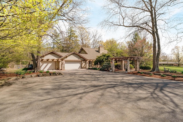 view of front of house featuring a chimney, a pergola, aphalt driveway, and a garage