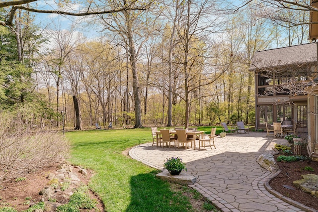 view of yard featuring outdoor dining area, a balcony, and a patio