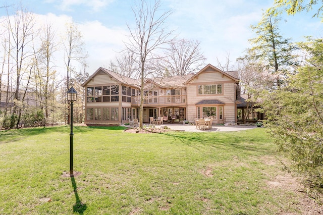 rear view of house featuring a lawn, a sunroom, a balcony, and a patio