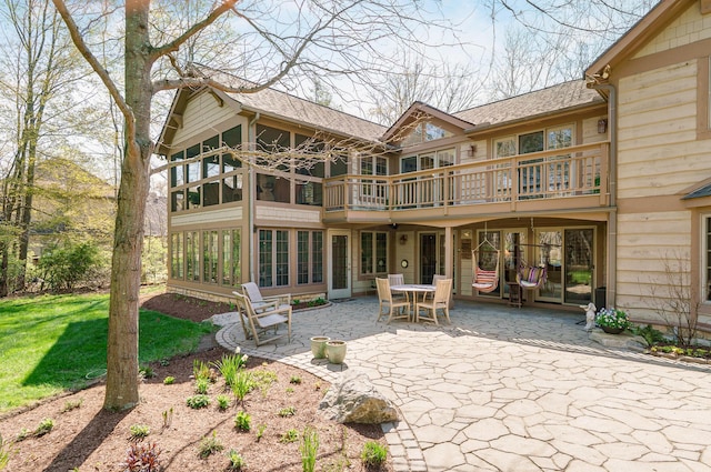 back of property with roof with shingles, a yard, a balcony, and a patio