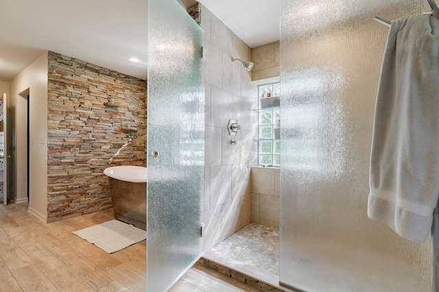 full bathroom with walk in shower, a freestanding tub, and wood finished floors