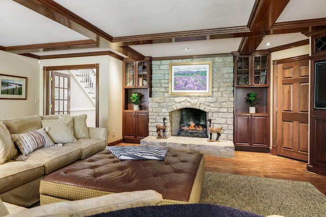 living area featuring light wood-type flooring, a stone fireplace, stairs, and crown molding