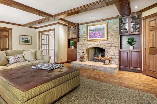 living area featuring baseboards, crown molding, light wood-type flooring, and a fireplace