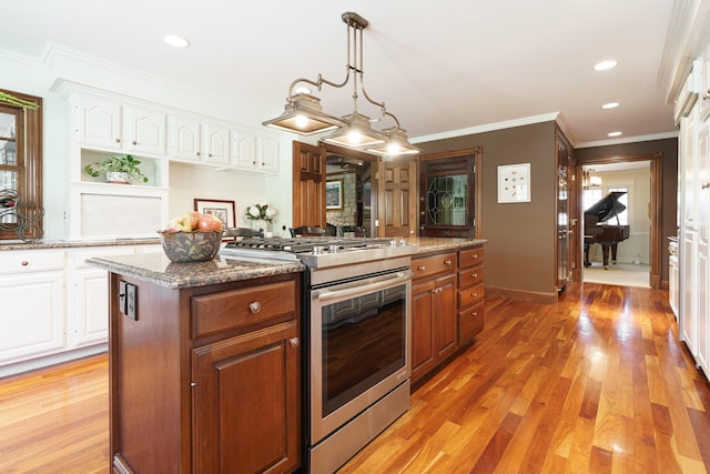 kitchen featuring white cabinets, a center island, gas stove, and light wood-type flooring