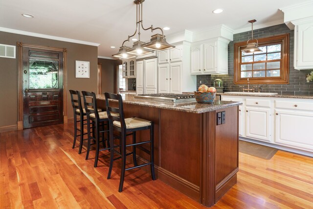 kitchen featuring a center island, a sink, stainless steel gas stovetop, decorative backsplash, and a breakfast bar