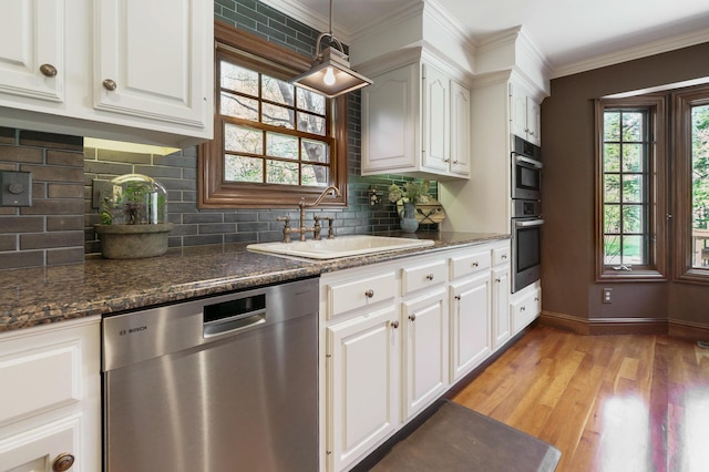 kitchen featuring a sink, light wood-style floors, baseboards, decorative backsplash, and appliances with stainless steel finishes